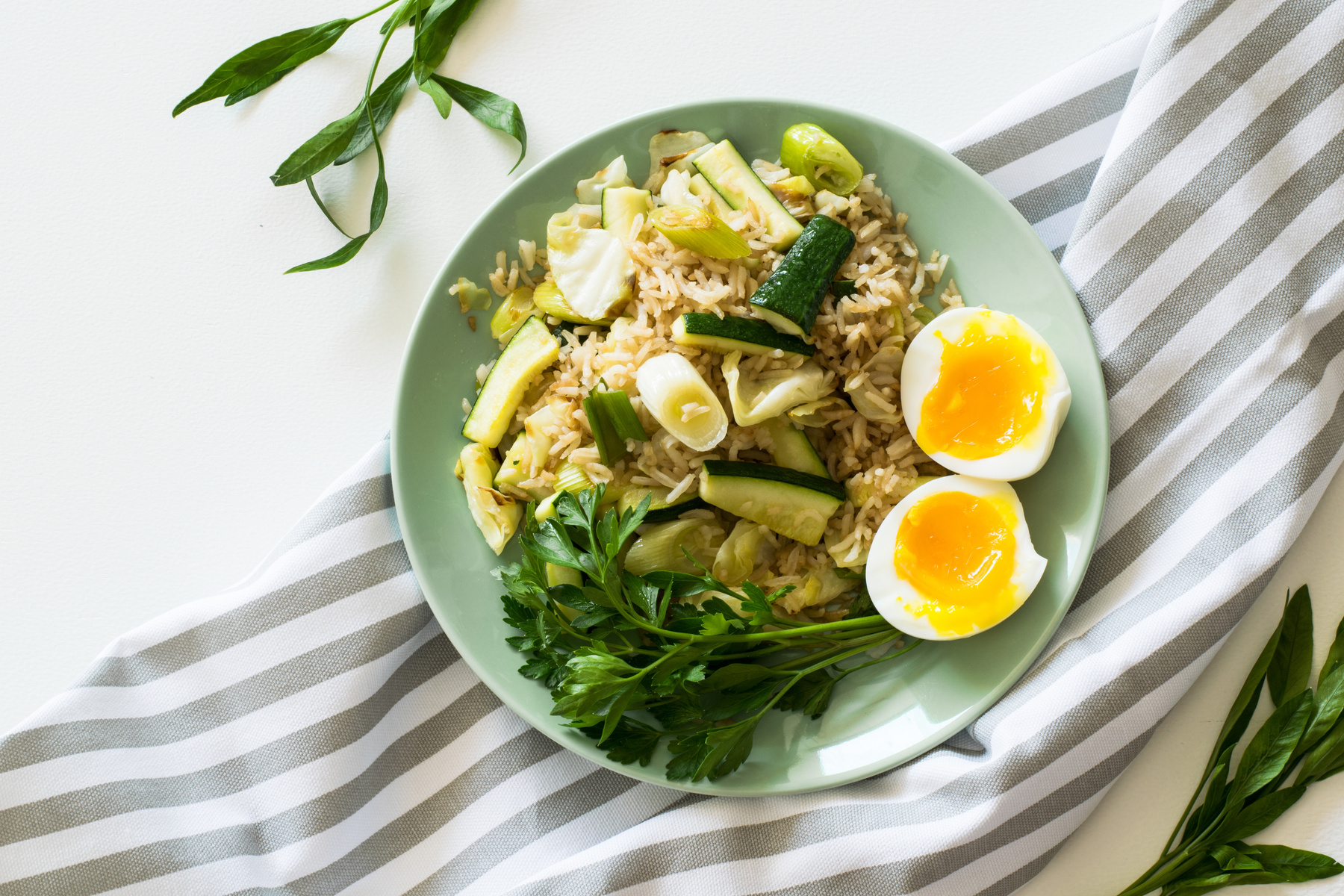 Fried Rice With Poached Egg, Zucchini, And Celery on Round Green Ceramic Plate